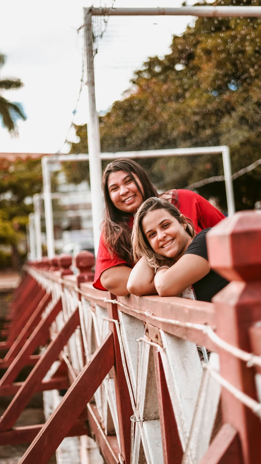 Two young women smiling over a bridge railing