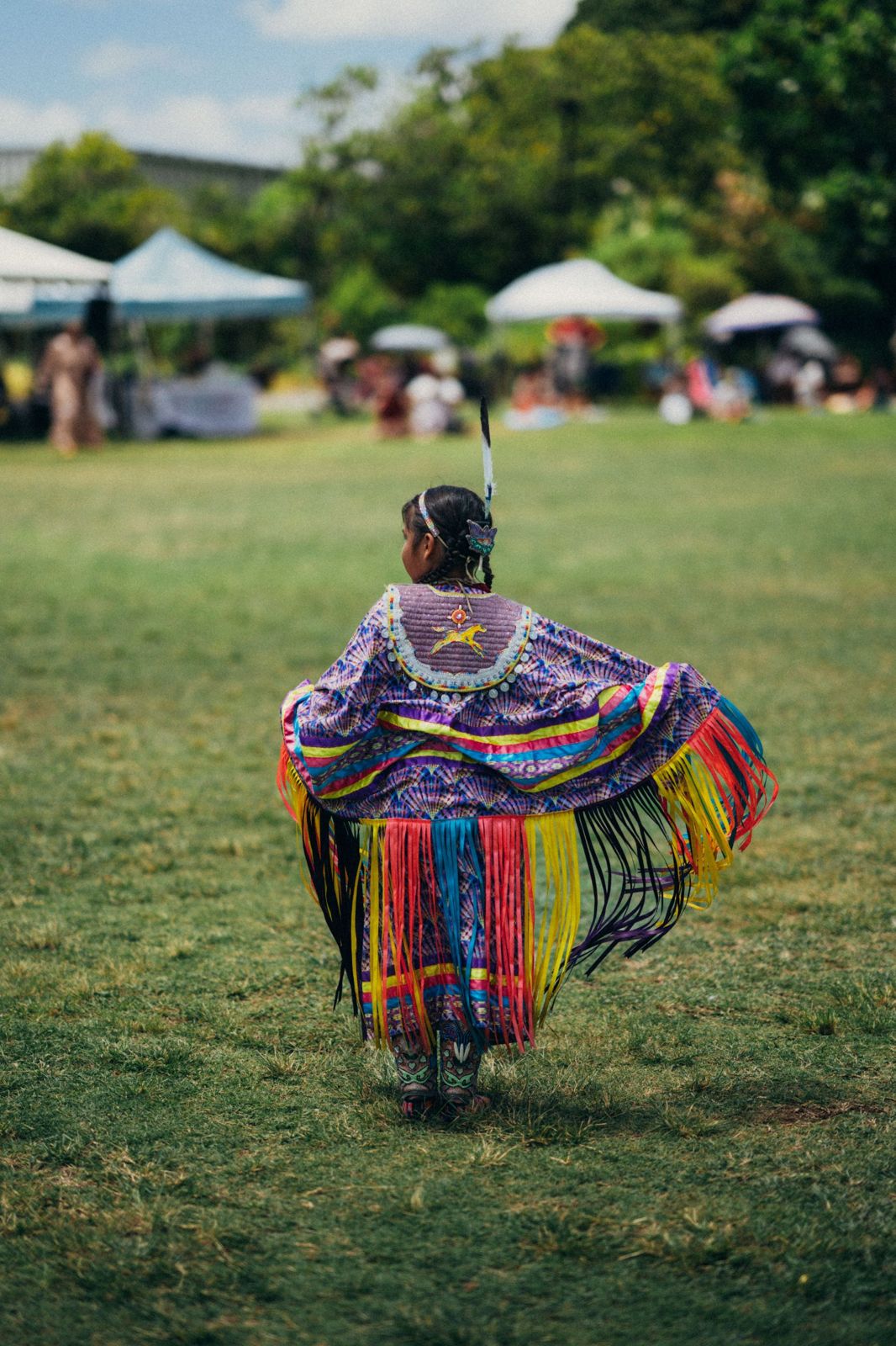 A young dancer in fringed regalia on a field