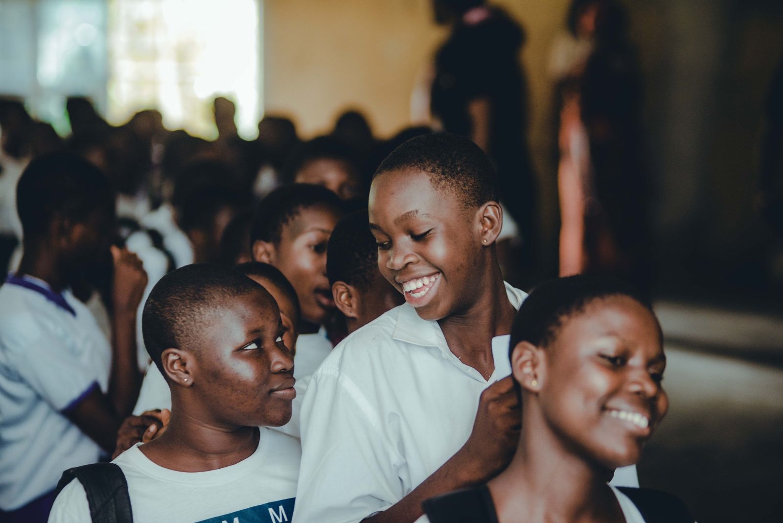 Three girls in white school shirts laughing together