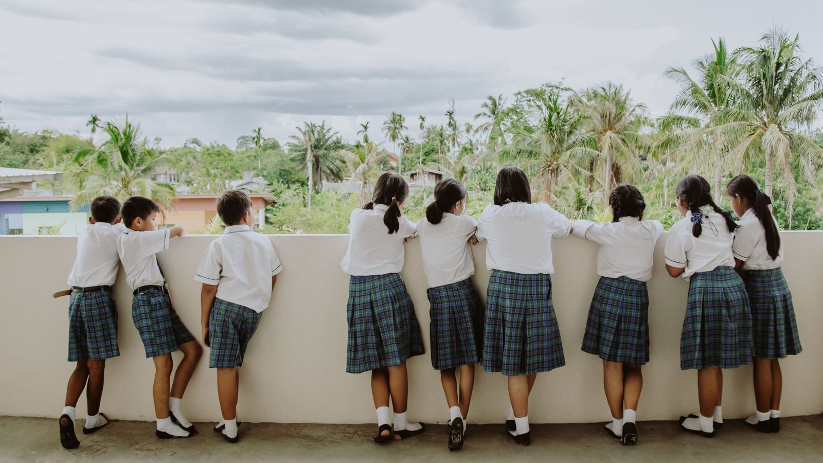 Students in uniform looking out from a school balcony